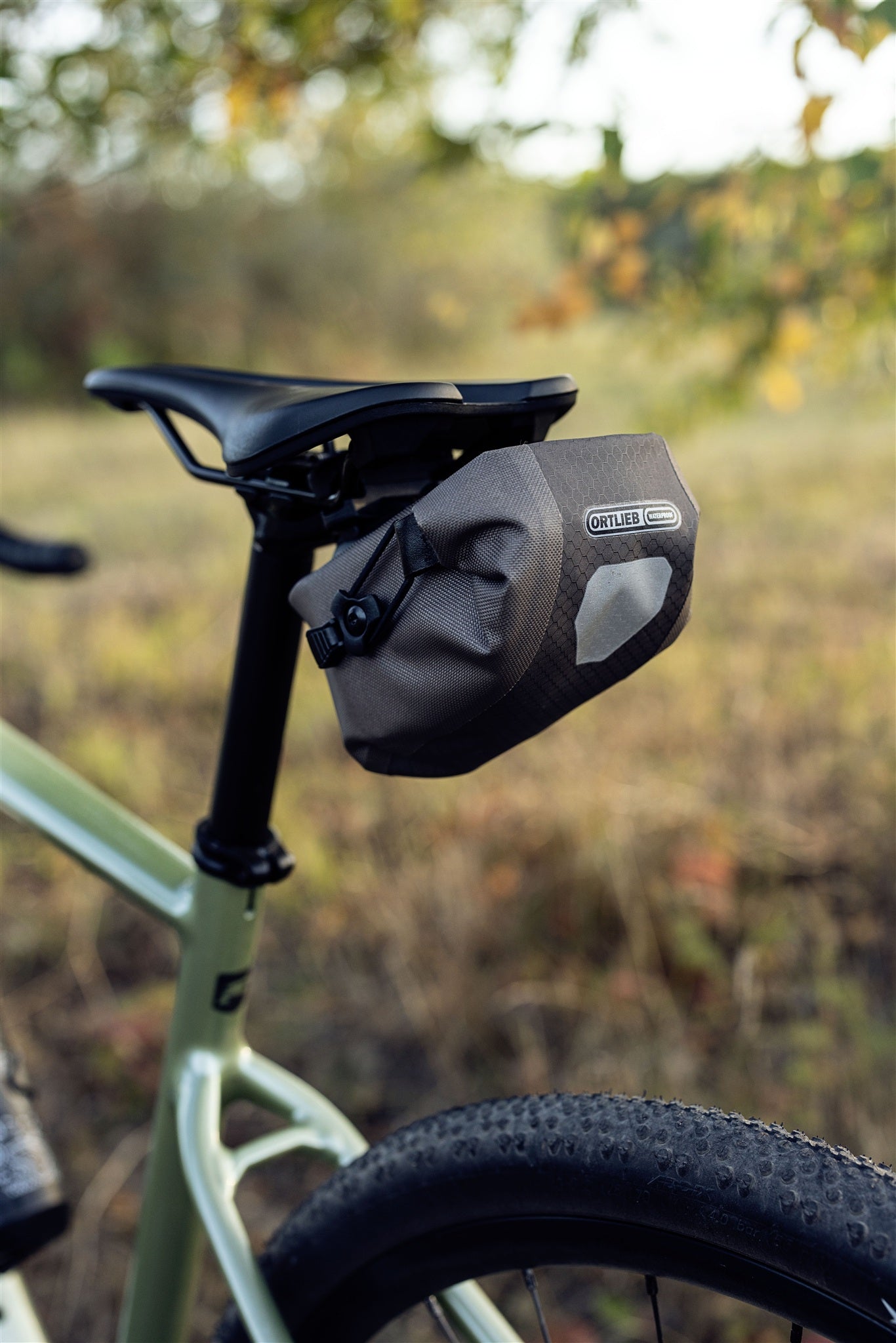 ORTLIEB Micro-Bag in dark-sand attached to bike saddle in outdoor setting